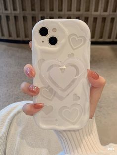 a person holding up a phone case with hearts on it