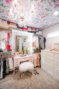 a closet with clothes hanging on the walls and a chandelier in the ceiling