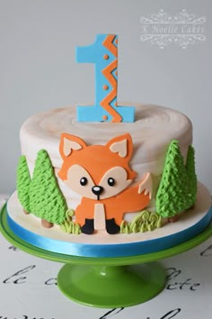 a first birthday cake with a fox and trees on it