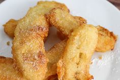 some fried food on a white plate with sugar sprinkled over the top and bottom