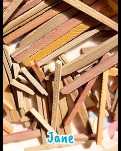 a pile of wooden clothes pegs sitting on top of a white table next to a sign that says jane