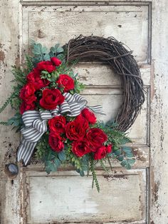 a wreath with red flowers and greenery on an old door