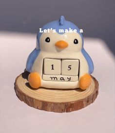 a penguin clock sitting on top of a piece of wood that says let's make a 1 5 may