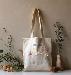 Carry a piece of your family garden wherever you go! 🌼🌿 Our custom tote bags feature your family name among beautiful blooms, celebrating the roots of love and togetherness. Perfect for gardening, picnics, or just spreading a little floral joy!" 🌸✨ *              100% cotton canvas * Heavy fabric (12 oz/yd² (406.9 g/m * Sewn-in label * Available in natural and black colors *               Size 15"x16" Tote Bag Custom, Flower Tote, Custom Christmas Gifts, Gift Flower, Family Garden, Custom Tote Bags, Black Handle, Beautiful Blooms, Custom Christmas