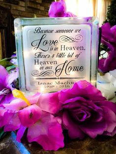 some flowers and a glass block with a quote on it that says, because someone is love in heaven there's a little bit of heaven in our home