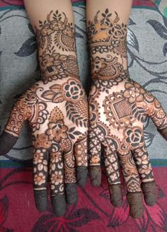 two hands with henna tattoos on them, one is showing off the intricate design