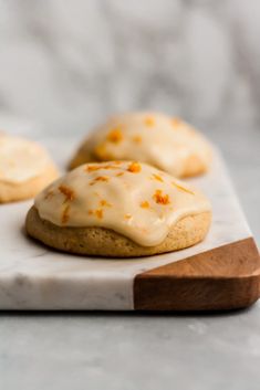 cookies with white icing and orange sprinkles on a marble cutting board