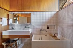 a bathroom with a tub, sink and mirror next to a stool on the floor