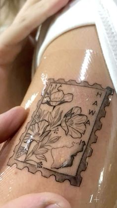 a woman's leg with a tattoo on it that has flowers in the frame