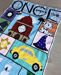 a crocheted blanket with cars and buildings on it that says once upon this