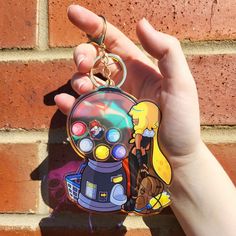 a hand holding a keychain with a cartoon character on the front and back