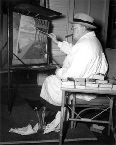 an old man sitting in front of a tv holding a paintbrush and painting on the easel