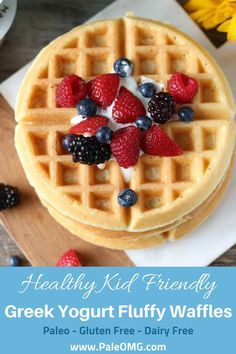 a waffle topped with berries and blueberries on top of a wooden cutting board