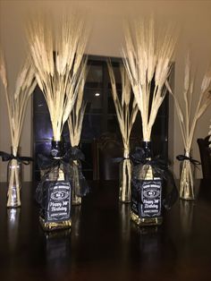 three vases filled with dried wheat on top of a table