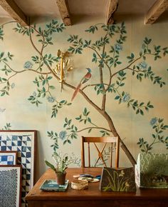 the wall paper has birds on it and there is a tree with green leaves painted on it