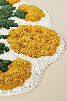 the rug is made up of yellow and green flowers on white doily with crocheted edges