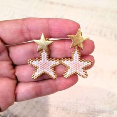 a person holding two gold and white stars in their hand, one is pink and the other is yellow