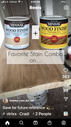 two tins of wood stain sitting on top of a wooden table next to each other