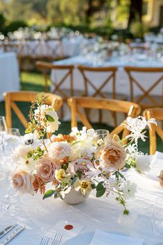 a vase filled with flowers sitting on top of a table next to glasses and silverware