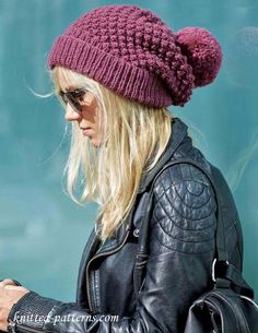 a woman wearing a knitted hat while looking at her cell phone and texting