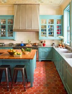 a kitchen with blue cabinets and wooden counter tops, an island in the middle has fruit on it