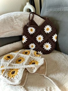 a crocheted sunflower bag sitting on top of a bed next to pillows