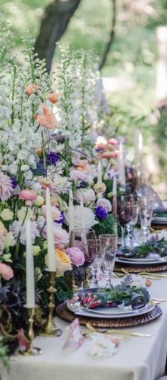 a long table is set with flowers and candles for an outdoor dinner party or celebration