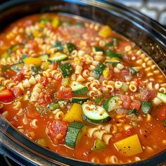 a bowl of pasta soup with zucchini, tomatoes and cucumbers in it