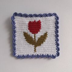 a crocheted square with a red rose on it