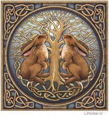 two brown rabbits sitting next to each other on a blue and gold tile with celtic designs