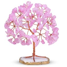 a pink crystal tree sculpture sitting on top of a rock