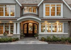 a large house with lots of windows and lights on it's front door, in the evening