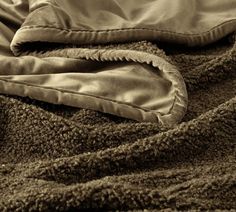 an unmade bed with a blanket and pillow on it's side, in sepia tone