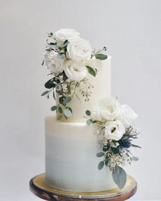 two tiered wedding cake with white flowers and greenery