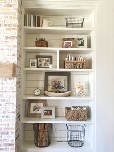 a white book shelf with baskets and pictures on it