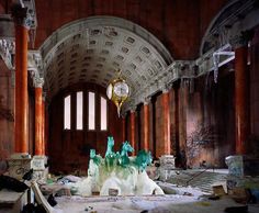 an abandoned building with many pieces of art on the floor and in front of a clock