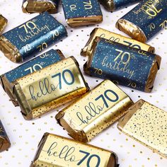 gold and blue birthday candy wrappers with the words hello 70 on them are scattered around