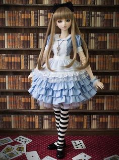 a doll is standing in front of a bookshelf with cards on the floor