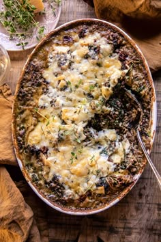 a casserole dish with cheese and herbs on the side, ready to be eaten