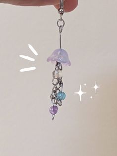 a hand holding a small purple and blue beaded charm on a silver plated chain