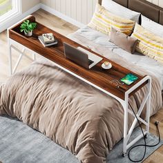 a laptop computer sitting on top of a wooden desk next to a bed in a bedroom