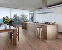 an open kitchen and dining area with wooden flooring overlooking the ocean is pictured in this image