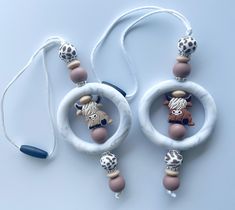 two necklaces made out of beads with animals in them on a white table next to a blue cord