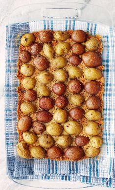 a square dish filled with potatoes on top of a blue and white towel