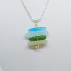 a necklace with three different colored glass pieces hanging from it's chain on a white surface