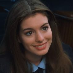 a close up of a person wearing a suit and tie with long hair smiling at the camera