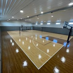 an indoor basketball court with wooden floors and lights on the ceiling is pictured in this image