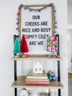 a shelf with some books and decorations on it in front of a sign that says our cheeks are nice and rosy comfy cozy are we