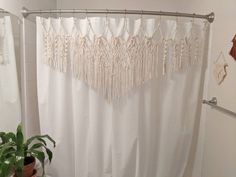 a white shower curtain with tassels hanging from it's side in a bathroom