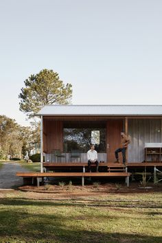 two people sitting on the porch of a small cabin